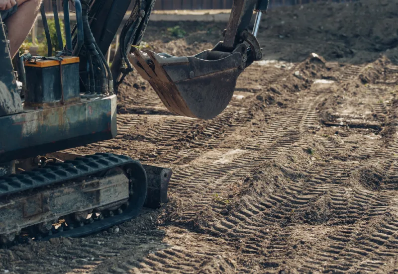 Excavator mechanical part for digging for construction. close up of tracked wheel on a construction site with yellow sandy soil