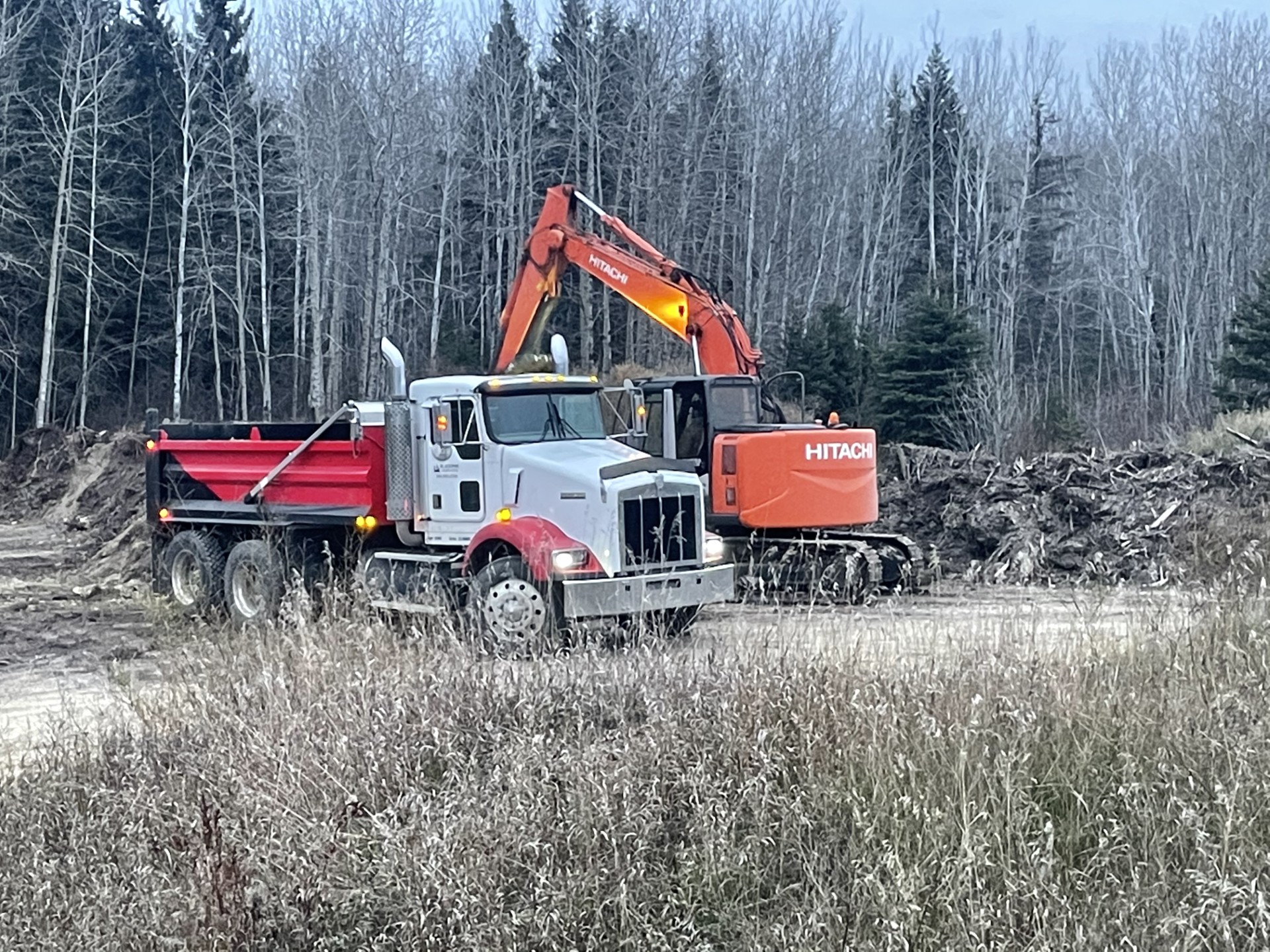 Dump truck unloads soil with crashed stone.